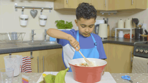 A young book preparing food in a kitchen