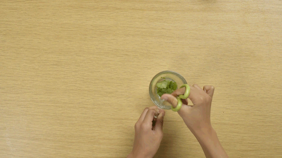 Hands using scissors to cut up herbs.